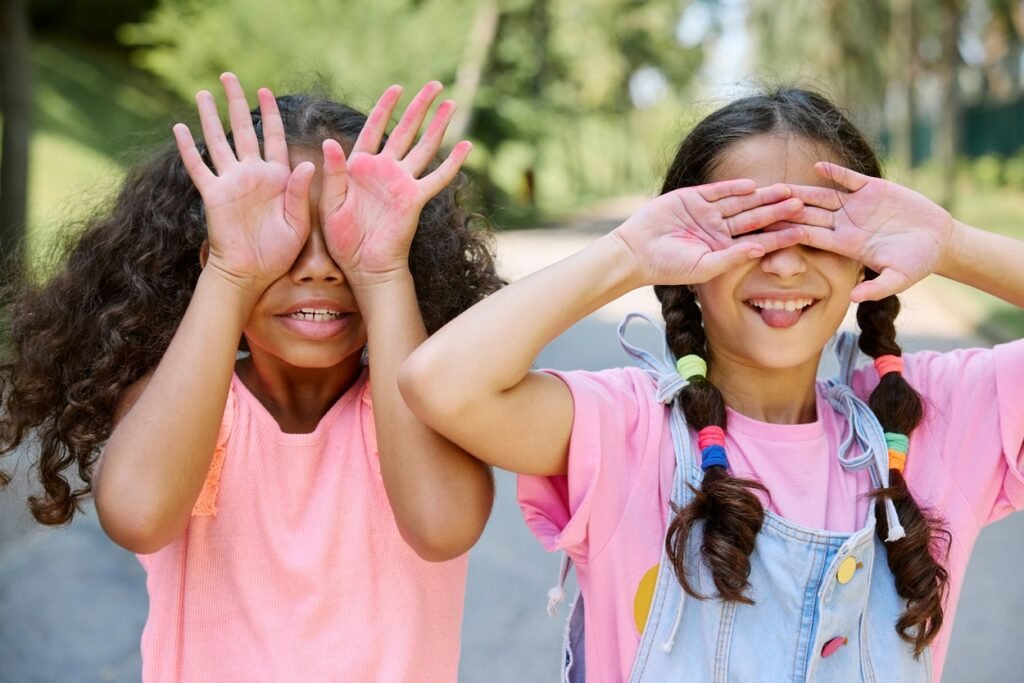 Two baby girls covering their eyes.