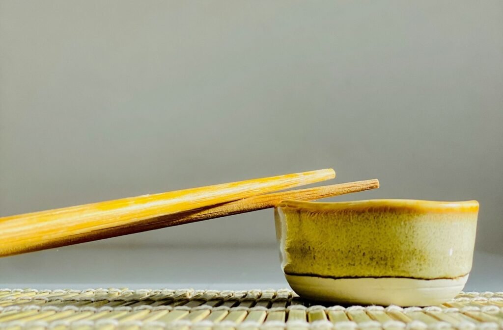 A pair of chopsticks with a yellow bowl.