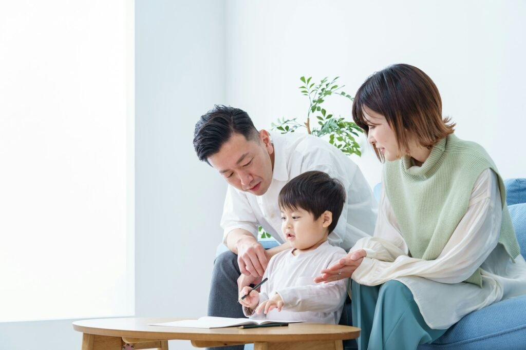 A boy is drawing a picture with his parents watching.