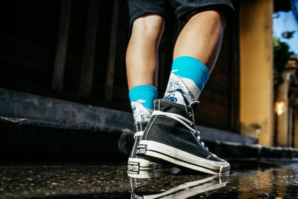 Man wearing a black shoe walking on a wet road.