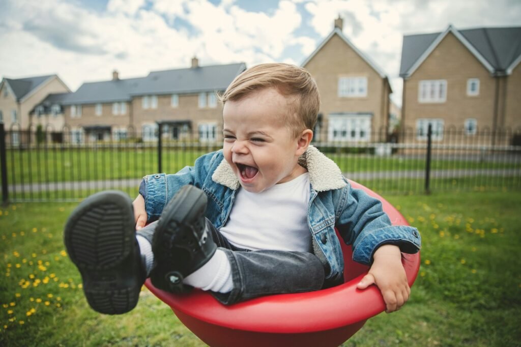 Little boy sitting on a red swing.