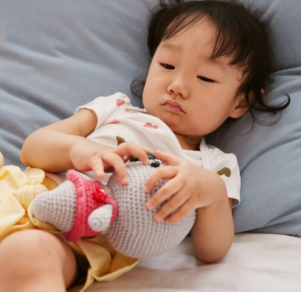 A little girl lying in the bed holding her favorite toy.