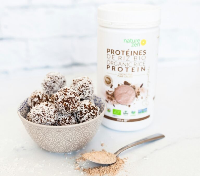 Protein powder in a tub and in a spoon.