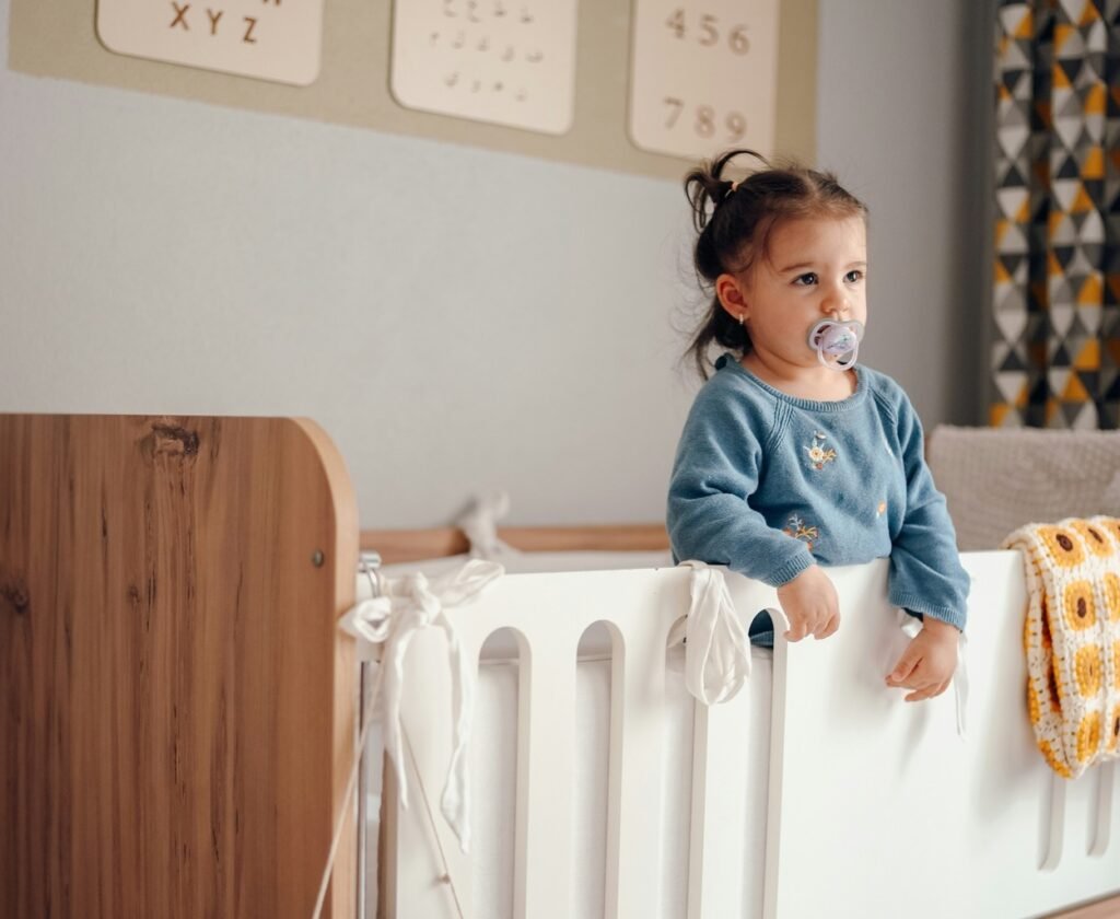 Little girl standing on the crib.