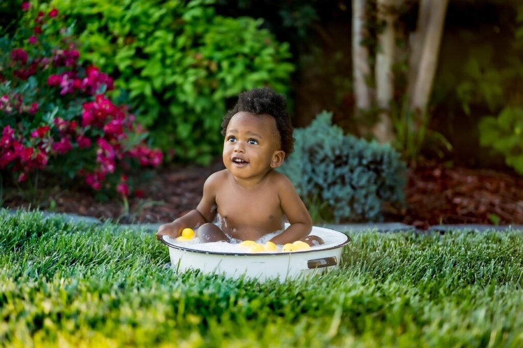 Little baby in a bowl filled with bubble and toys.