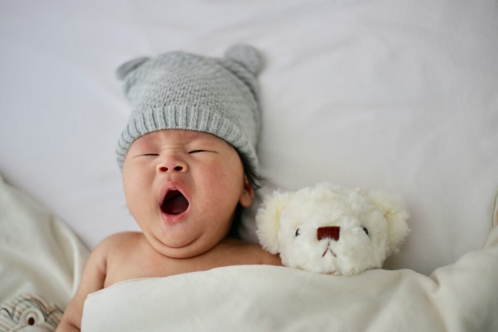 A baby is sleeping with his favorite doll by his side.